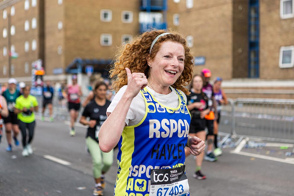 An RSPCA fundraiser wearing a white t-shirt and RSPCA running vest taking part in a charity running event.